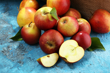 Ripe red apples with leaves on blue background.