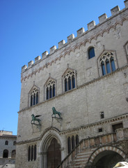 Fototapeta na wymiar Facciata con merlatura finestre trifore e statue bronzee