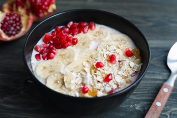 Yoghurt smoothie bowl with banana slices, oatmeal and pomegranate. Healthy diet meal for breakfast, low calorie food for weight losing and well-being