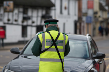 civil enforcement officer traffic warden issuing ticket to car parked incorrectly with fixed...