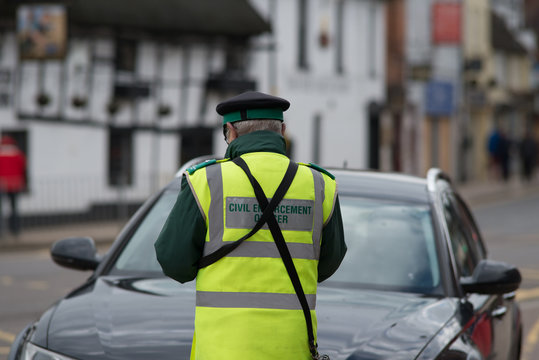 Civil Enforcement Officer Traffic Warden Issuing Ticket To Car Parked Incorrectly With Fixed Penalty Notice