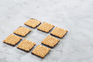 Square biscuits arranged in pattern on light textured background, close-up, shallow depth of field, selective focus.