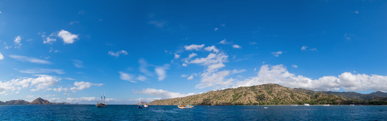 Obraz premium Panoramic blue sky background with white clouds on a sunny day over the sea in Komodo island, East Nusa Tenggara, Indonesia