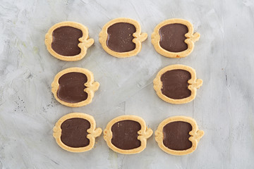 Apple shaped biscuits arranged in rows on light textured background, close-up, shallow depth of field, selective focus.