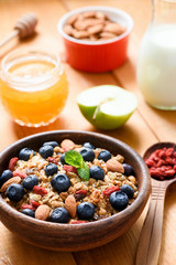 Muesli or granola in wooden bowl with blueberries, goji berries and almonds. Healthy lifestyle, healthy eating, dieting, vegetarian, fitness or weight loss concept