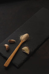 Photo with garlic powder and cloves on dark slate board