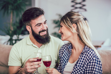 Beautiful romantic couple having romantic moments, drinking red wine while celebrating Valentine's Day or anniversary at home
