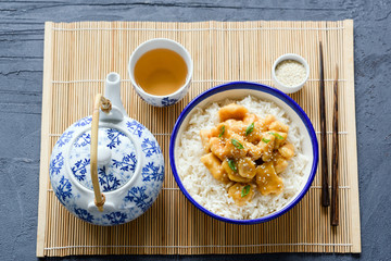 Chinese chicken with rice, chopsticks and green tea on bamboo sheet. Traditional asian cuisine