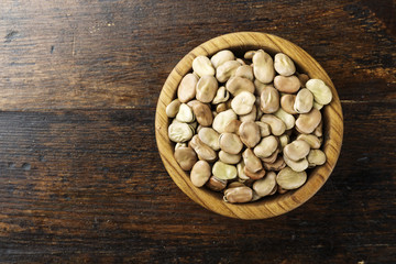 raw dry beans in a plate on a wooden background. top view.