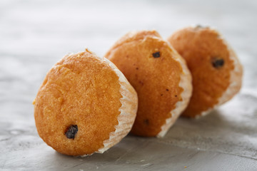 Tasty muffins arranged in pattern on light textured background, close-up, shallow depth of field, selective focus.