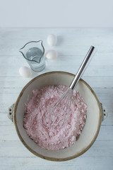 pink cake dry mix in bowl with eggs top view on clean white background