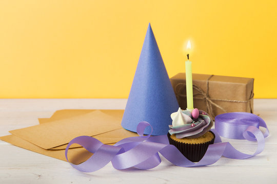 Delicious cupcake and gift on yellow background