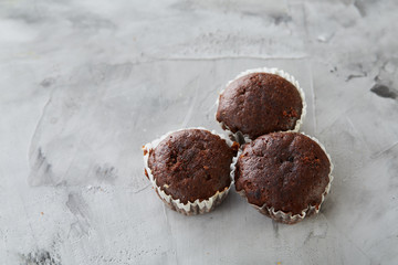 Tasty muffins arranged in pattern on light textured background, close-up, shallow depth of field, selective focus.