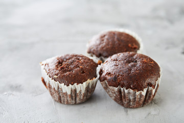 Tasty muffins arranged in pattern on light textured background, close-up, shallow depth of field, selective focus.