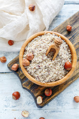 Hazelnut flour in wooden bowl and whole hazelnut.
