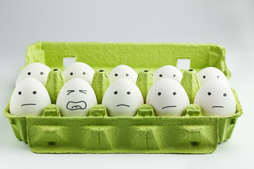 Eggs with drawn faces in eggbox. Concept of burnout, stress at work.