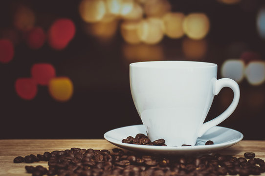 cup of coffee on wooden table with defocus bokeh of coffee shop background. Image with soft focus and blurred background.