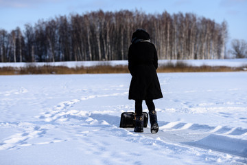 young woman in black coat cleaning ice from snow