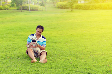 Happy Asian man playing with his dog in garden
