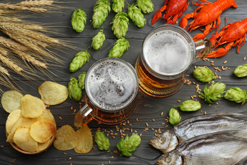 Glass beer with crawfish, dried fish and hop cones on dark wooden background. Beer brewery concept....