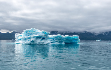 Greenland, Iceberg at a Fjord blue iceberg with with clear blue colour spots inside of it and also with dramatic mood of the sky in the atlantic ocean