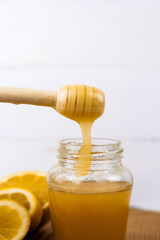 jar of honey and lemon slices on a wooden board light background