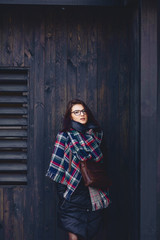beautiful girl in eyeglasses and a scarf against a wooden wall