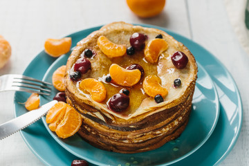 Pancakes with honey, cherries, wild berries and tangerines
