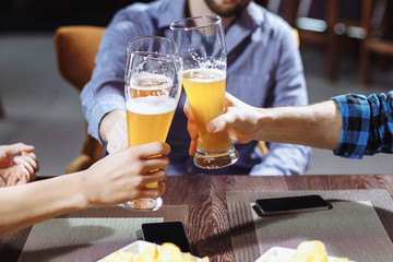 Three friends toasting with glasses of light beer at the pub