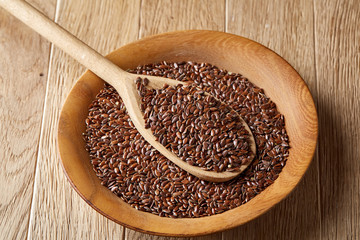 An overturned wooden bowl with linseeds on a rustic background, close-up, shallow depth of field, selective focus