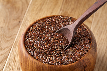 An overturned wooden bowl with linseeds on a rustic background, close-up, shallow depth of field, selective focus