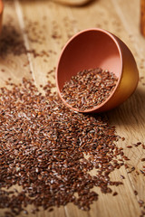 An overturned wooden bowl with linseeds on a rustic background, close-up, shallow depth of field, selective focus