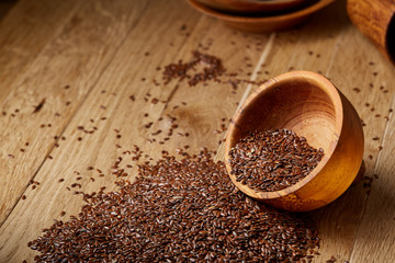 An overturned wooden bowl with linseeds on a rustic background, close-up, shallow depth of field, selective focus