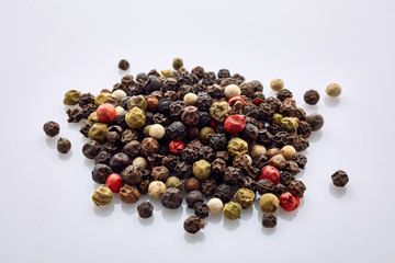 Top view on black, red and white peppercorns isolated on white background, shallow depth of field.