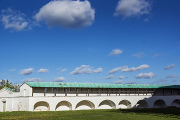 Fototapeta na wymiar White wall of the monastery against the background of excellent blue sky with clouds