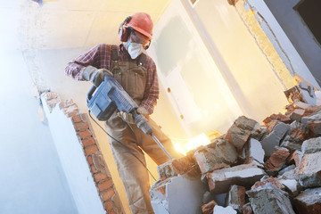 breaking interior wall. worker with demolition hammer