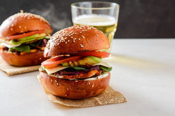 Homemade hamburger with lettuce, cheese, beef meat, grilled vegetables and beer.
