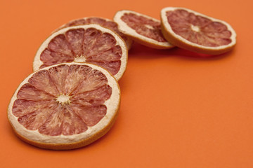 Fototapeta na wymiar dried rings of grapefruit on orange background
