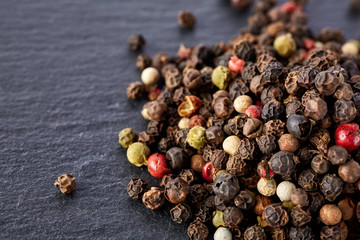 Top view on black, red and white peppercorns isolated on dark background, shallow depth of field.