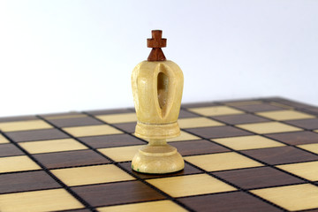 Lone chess white king on a chessboard on white background close-up