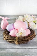 Fototapeta na wymiar Perfect colorful handmade easter eggs in a nest with spring flowers on a wooden gray background. Happy Easter