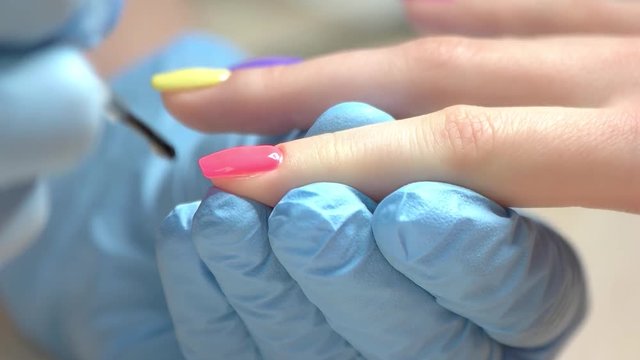 Close up hand covering nail with fixer. Specialist covers the nail of the client by fixer in nail salon, slow motion.