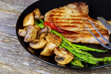 Grilled striploin steaks with mushrooms and green asparagus on a plate, selective focus,