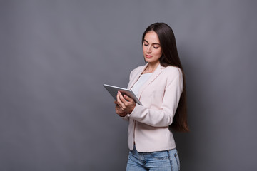 Pretty girl with tablet on gray background