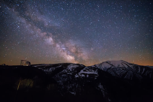 Starry sky with milky way over Caucasian mountains and observatory