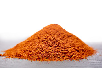 Red ground paprika on dark grey background, shallow depth of field, backlight.
