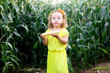 little girl in the middle of a cornfield with a corn cob
