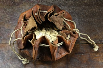 Swiss Vreneli gold coins in a leather purse on rustic wooden background