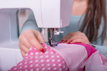 Young girl is sewing a pink patchwork blanket