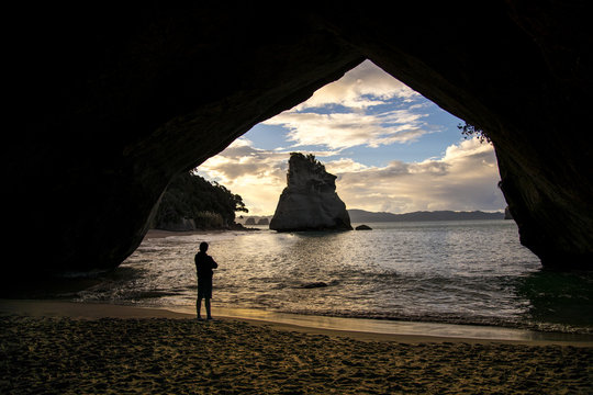 A man gazes out at Cathedral Cove from inside a cave on the Coromandel Peninsula near Auckland, New Zealand